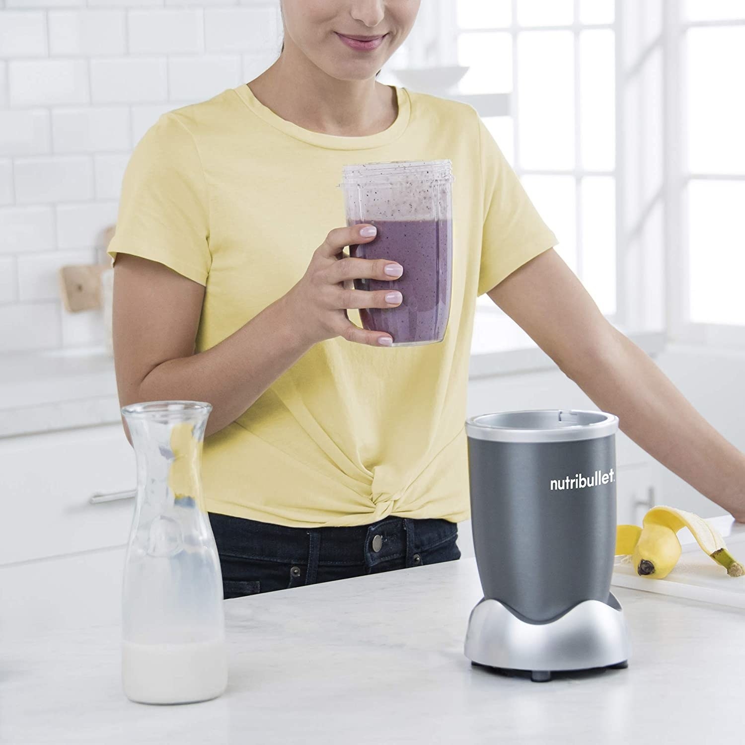 A model drinking a smoothie out of the NutriBullet cup 