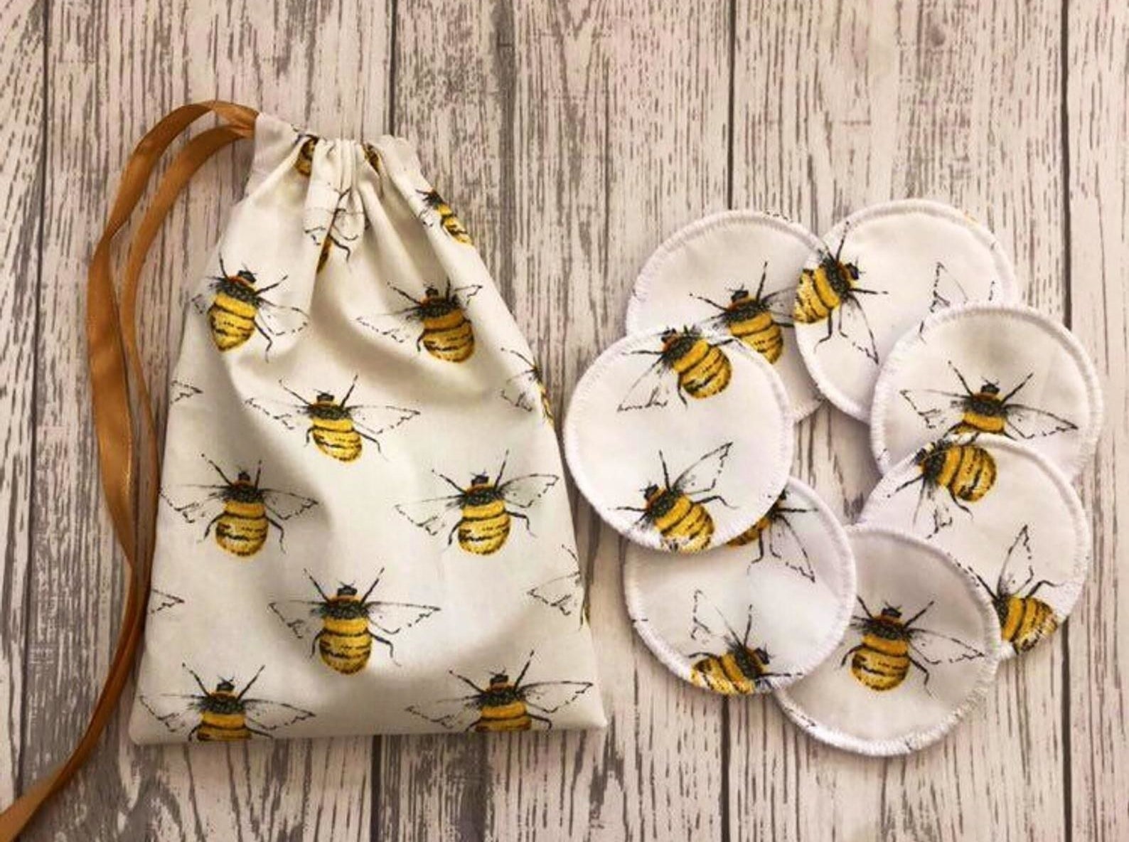 A set of seven round pads and a drawstring bag made with a beige fabric with illustrations of bees all over them