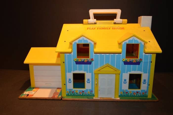 A Fisher-Price Little People play house with a yellow roof and blue walls.