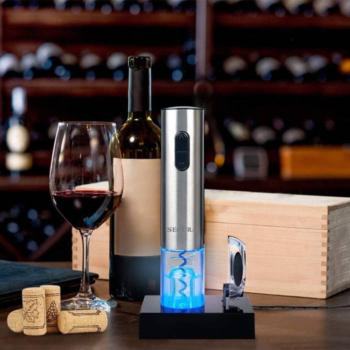 The tube-shaped metal wine opener next to a bottle of wine it just uncorked 