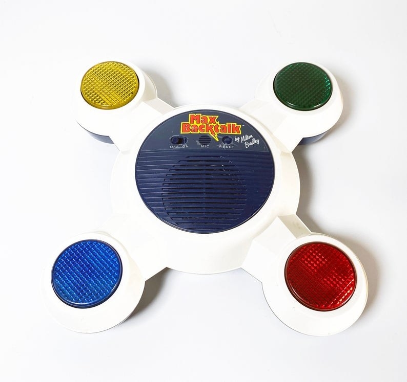 A Max Backtalk game which is white and features four different colored lights (yellow, green, red, and blue) on extended arms.