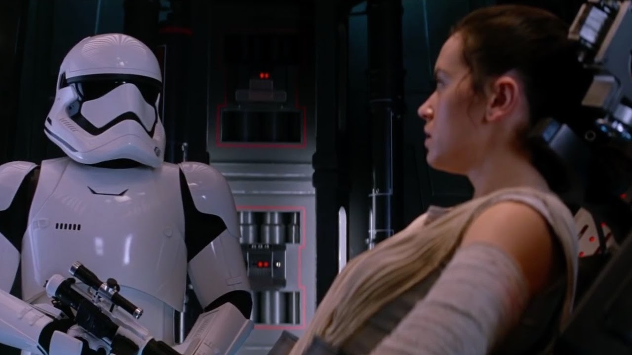 A stormtrooper stands over a captive Rey 