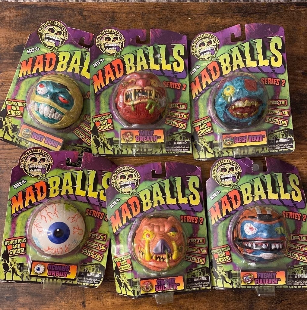 Six different Madballs in its original packaging on a wooden table.