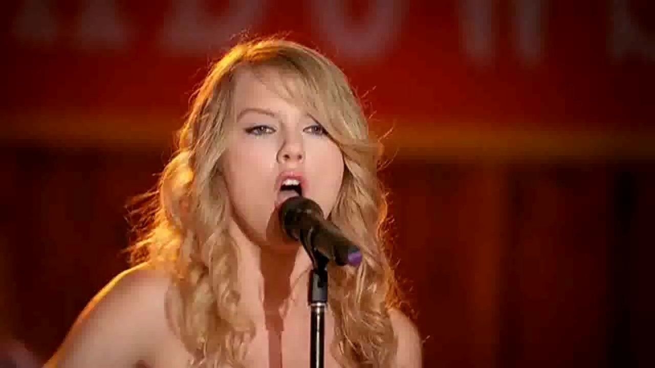 Taylor Swift sings at a microphone