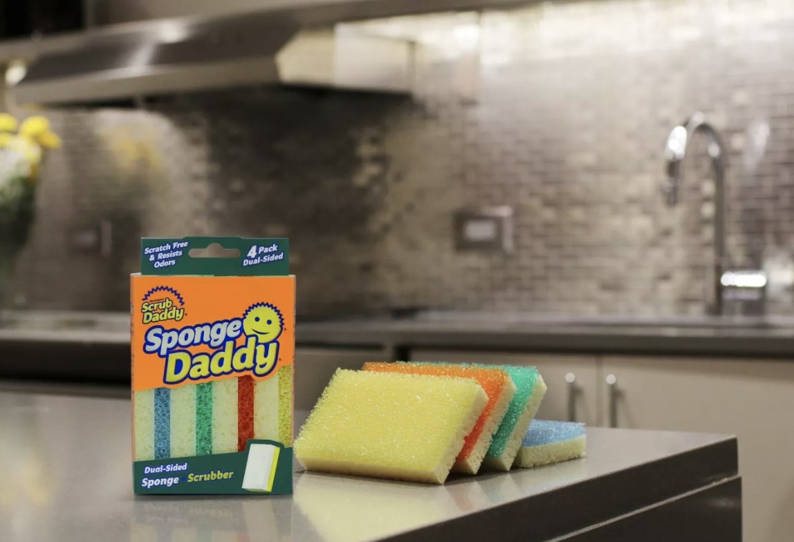 Yellow, orange, green, and blue Sponge Daddy sponges on a kitchen countertop