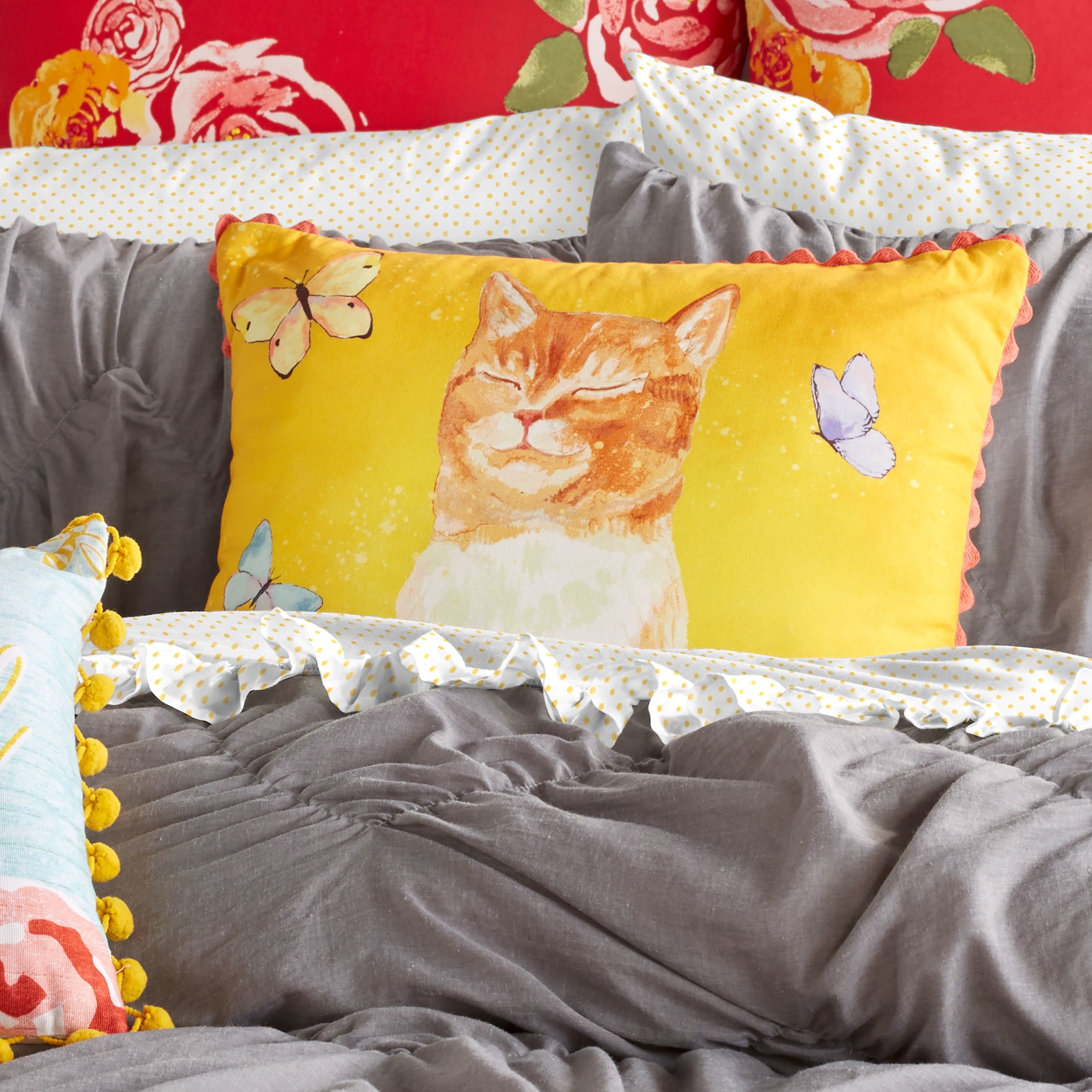 The pillow is yellow and features a cat with its eyes closed and butterflies 