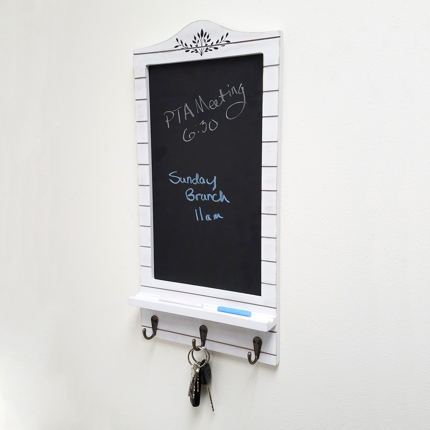 The chalkboard has a wooden white frame and three key hooks