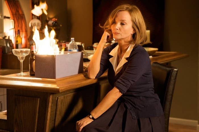A woman sitting nonchalantly at a bar as a box in front of her is set on fire