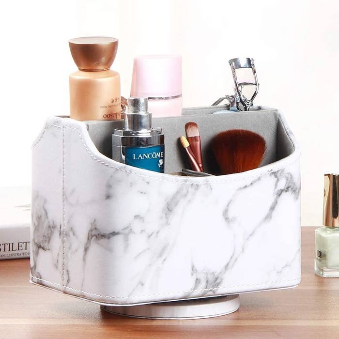 A spinning caddy on a desktop filled with makeup brushes skincare and an eyelash curler