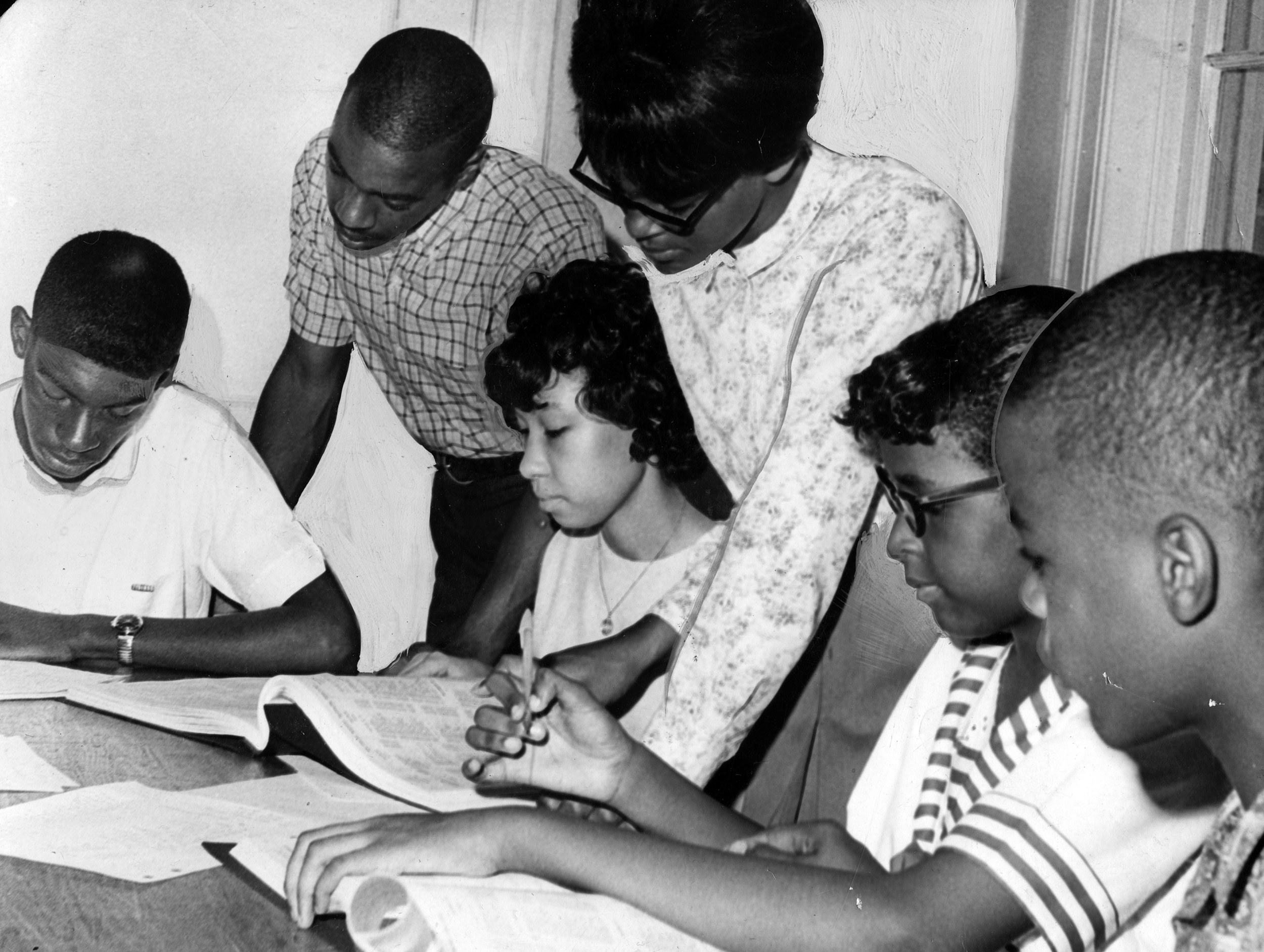 A group of black people at a table look at books