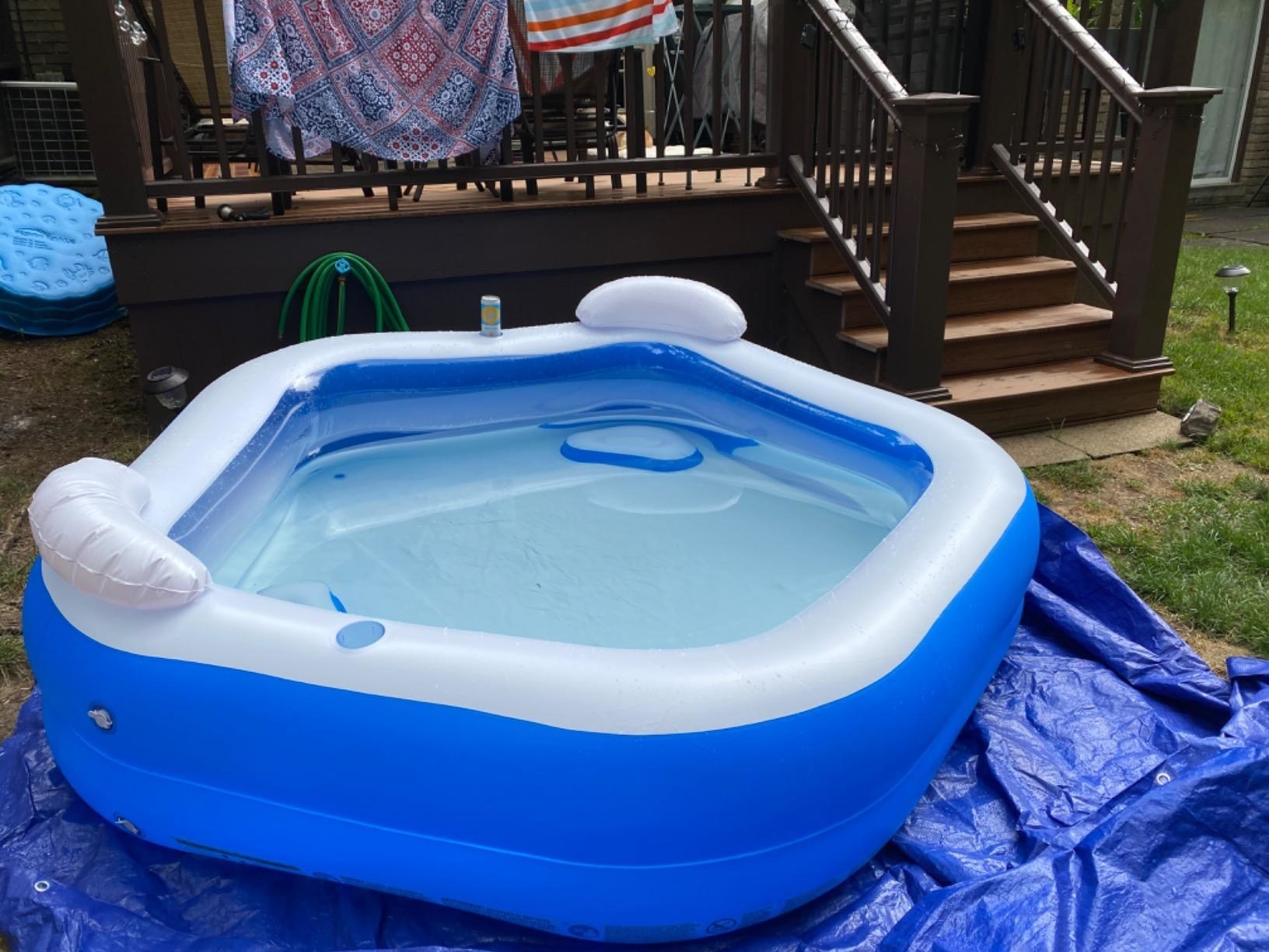 A reviewer showing that the pool has two backrests and cup holders in the side