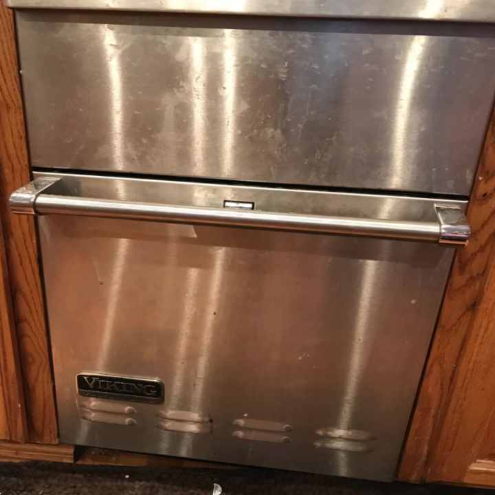 A dirty stainless steel dishwasher with streaks, buildup, and marks
