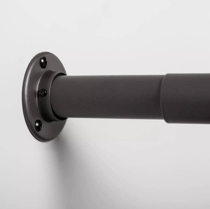 A close-up of the extendable side of a dark gray closet rod