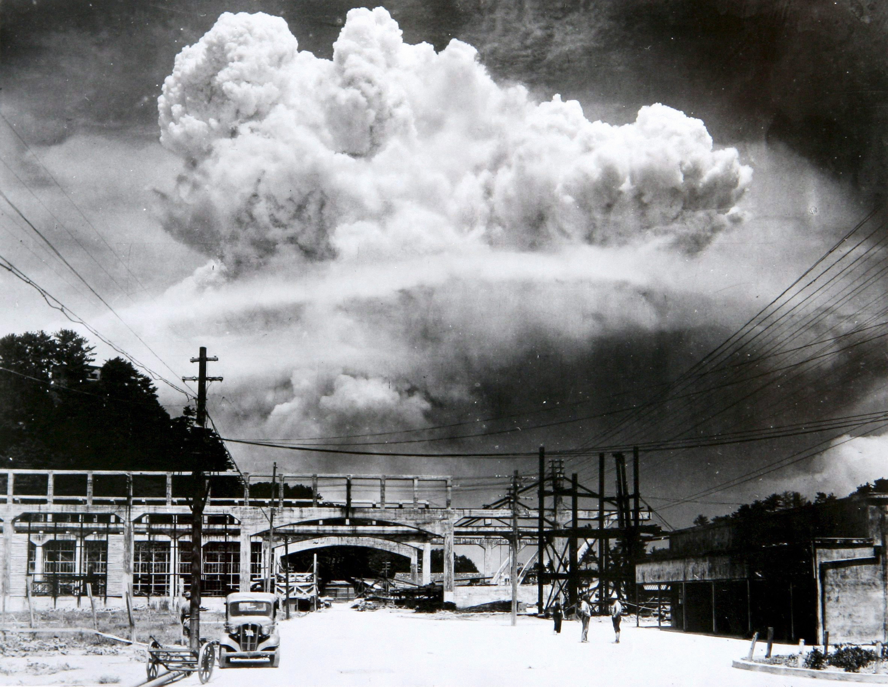 A gigantic atomic mushroom cloud explodes over a bridge and railway station