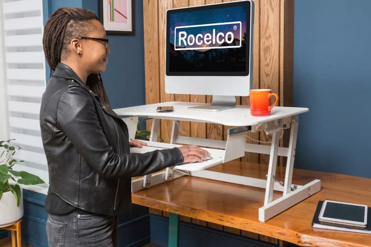 A model using a white standing desk propped on a table 