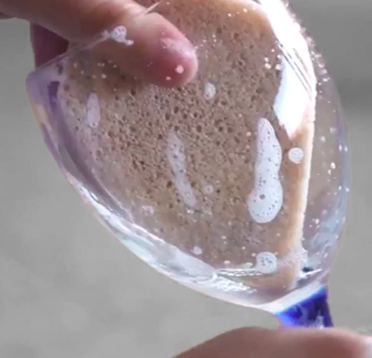 Hand uses stink-free vegan sponge to clean the inside of a wine glass
