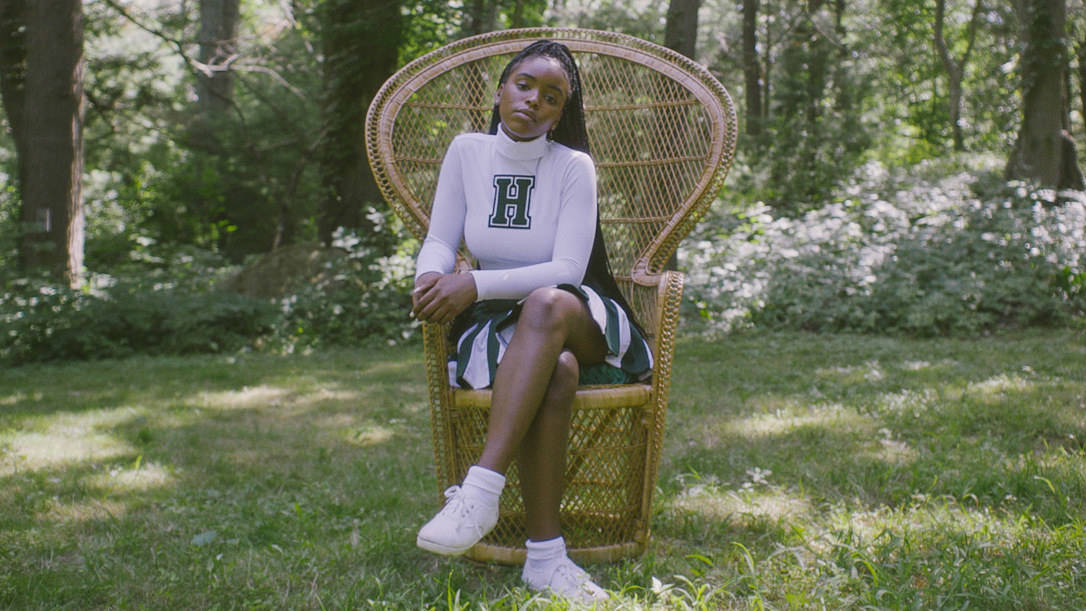 Selah played by Lovie Simone looks regal as she sits on a chair on a grassy field and stares at the camera 