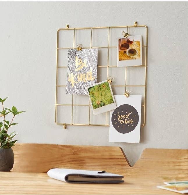 The square organizer on a wall with photos and postcards clipped to it