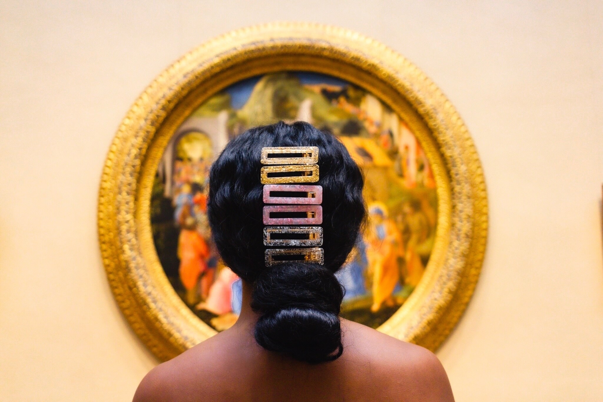 model with two gold, two pink, and two silver flecked rectangular hair clips going down the back of their head