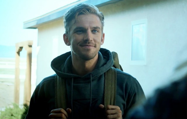 Dan Stevens wears a hoodie and backpack and smiles as David Collins in the movie The Guest