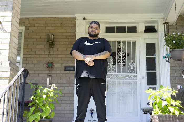 Boykin, who is Black, stands on the front porch of his parent&#x27;s house wearing a Nike shirt and pants with his arms crossed after being released from prison