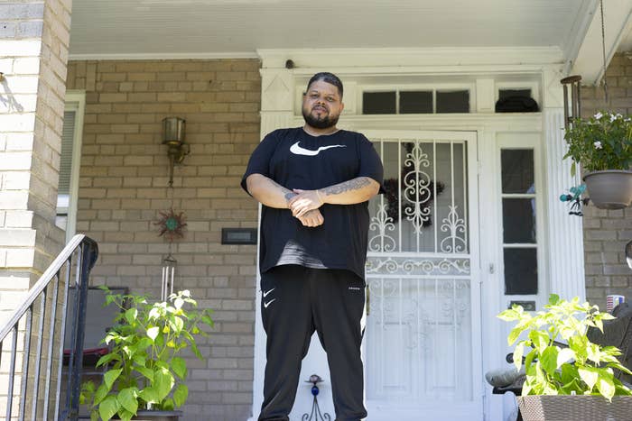 Boykin, who is Black, stands on the front porch of his parent's house wearing a Nike shirt and pants with his arms crossed after being released from prison