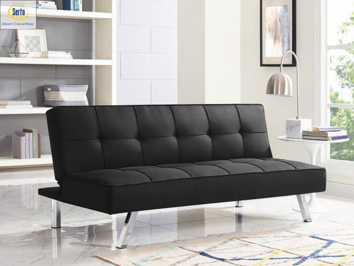 The futon in black, featuring chrome legs and fabric upholstery 