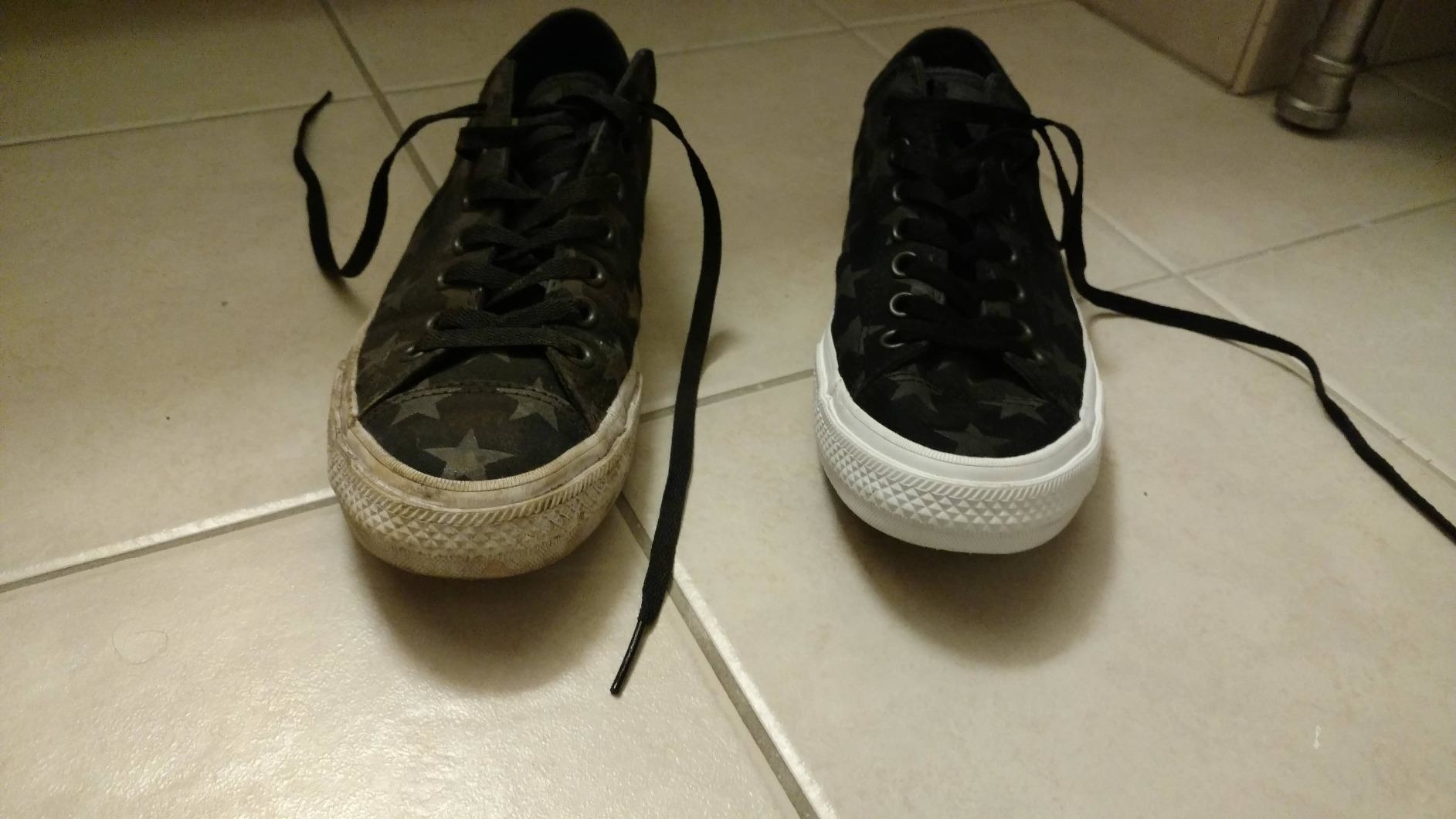 A pair of sneakers, the left one with completely dirty soles, and the right with white, new-looking soles