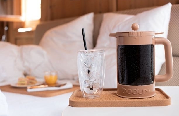 the cold brew maker next to a glass of ice and a cozy breakfast in bed set up