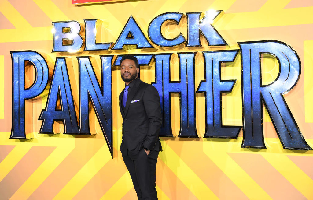 Ryan Coogler standing in front of a Black Panther sign at the film premiere