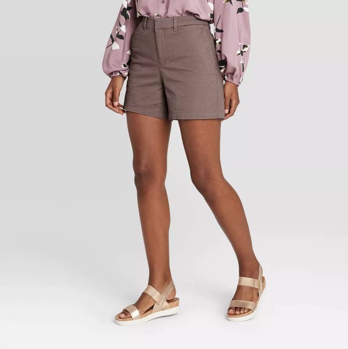 Model is wearing a pair of high-waisted pale purple 5-inch chino shorts with metallic chunky sandals 