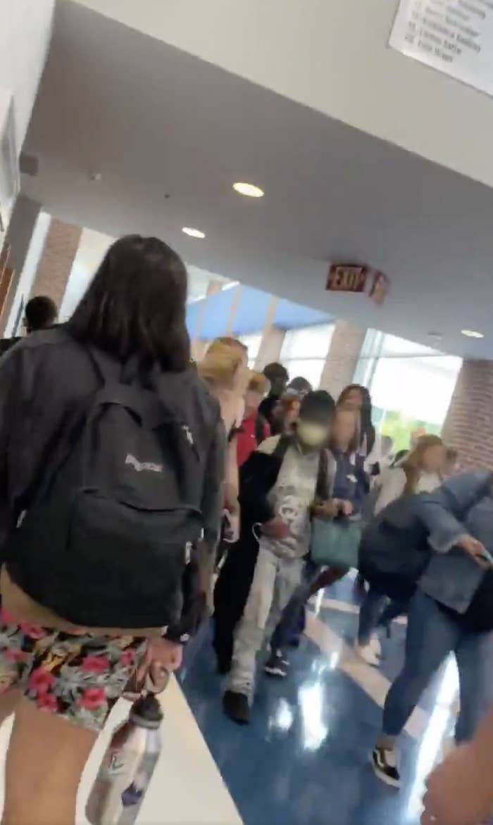 Students with blurred faces walk in a crowded school hallway
