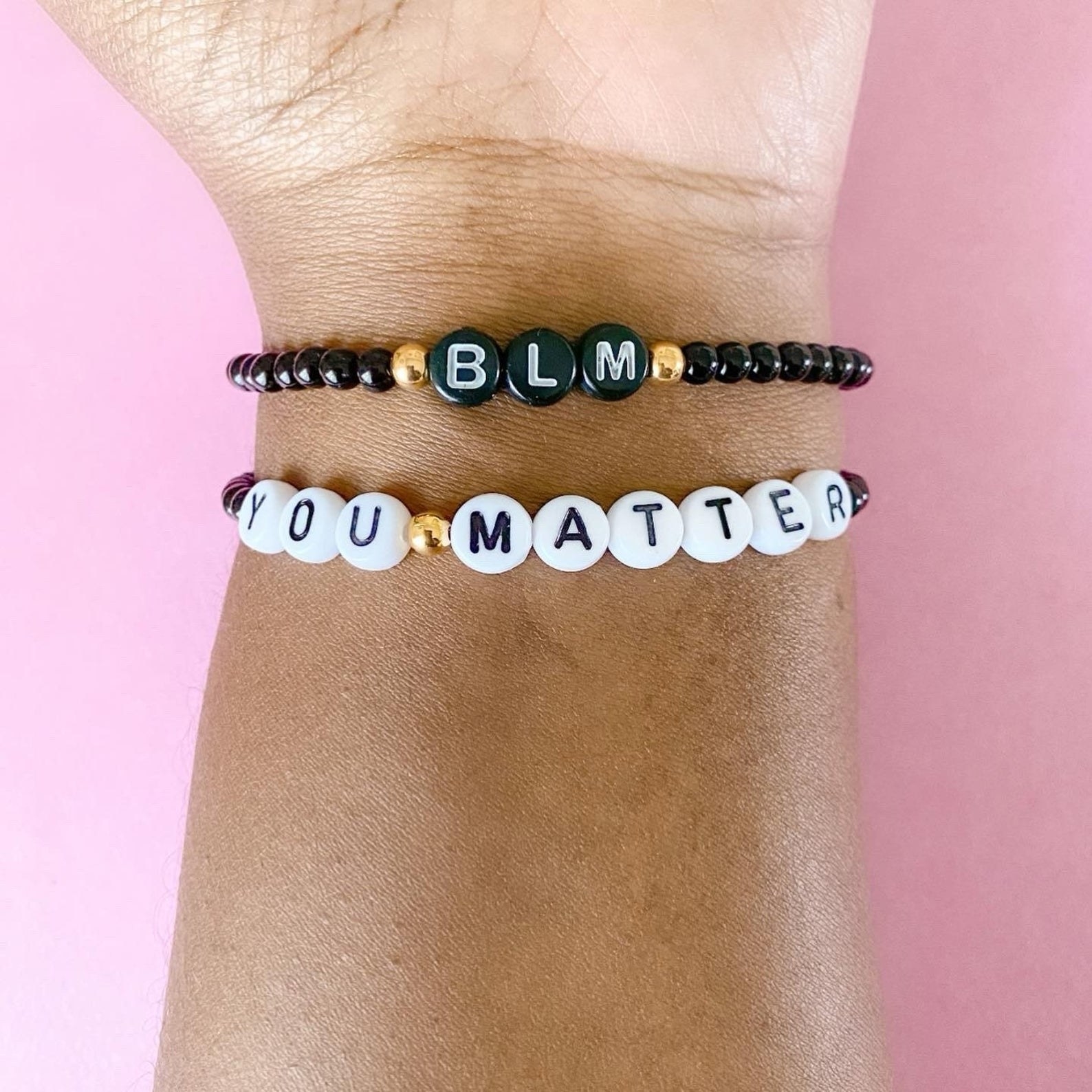a black bracelet that says BLM on it above a white bracelet that says you matter