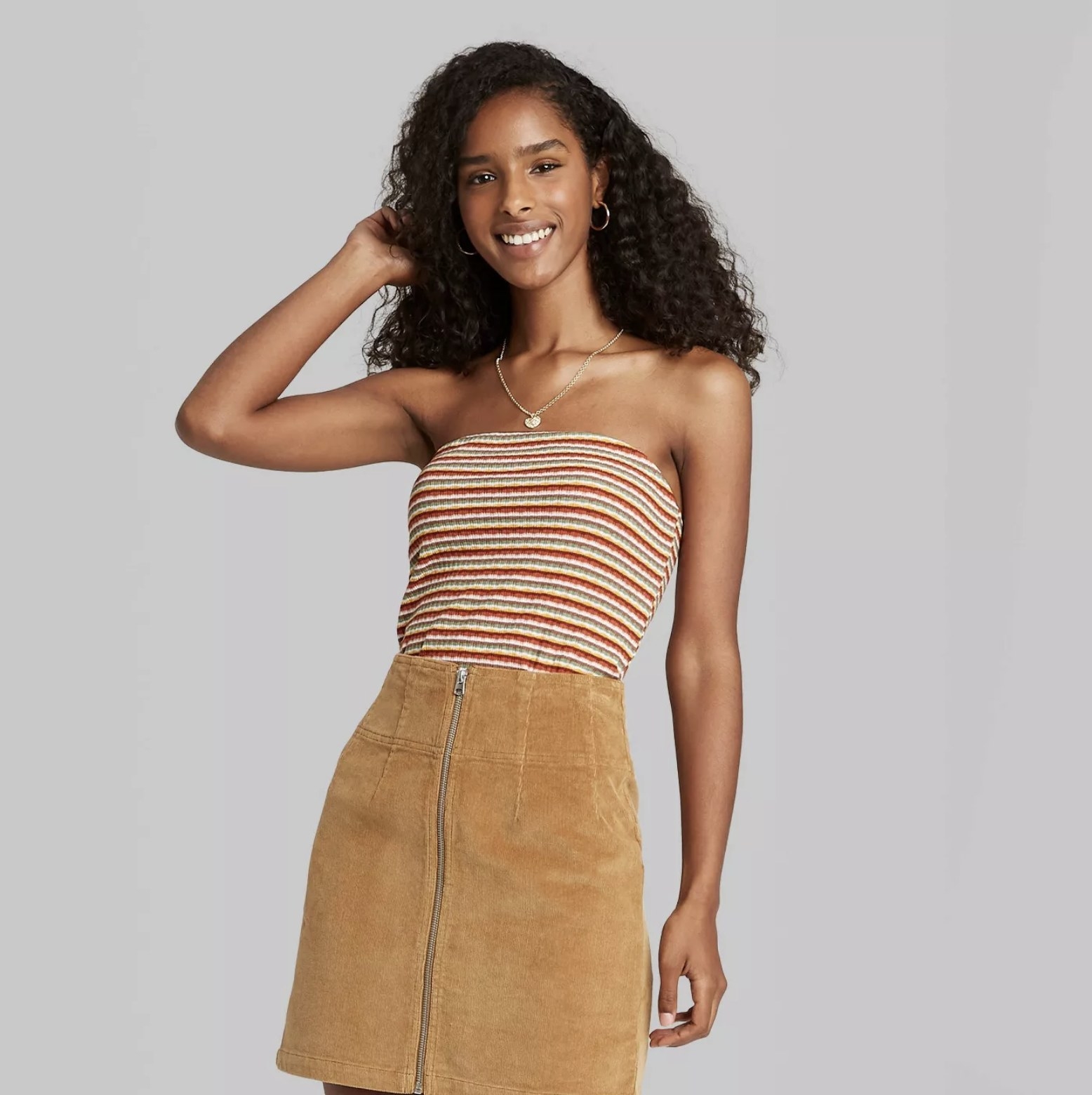Model is wearing a cropped burnt orange, light grey, and cream striped tube top with a textured rib pattern