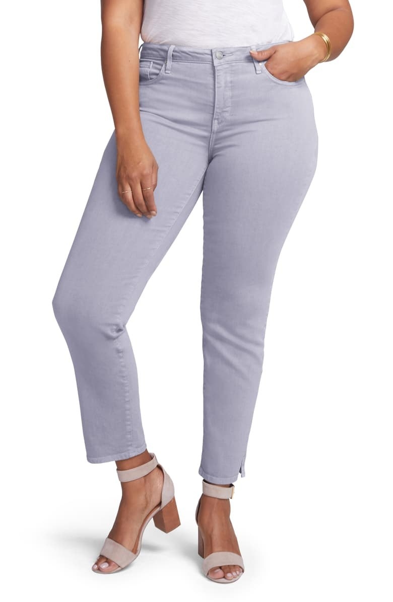A plus size model wears the Curves 360 slim straight leg ankle jeans in mineral pigment