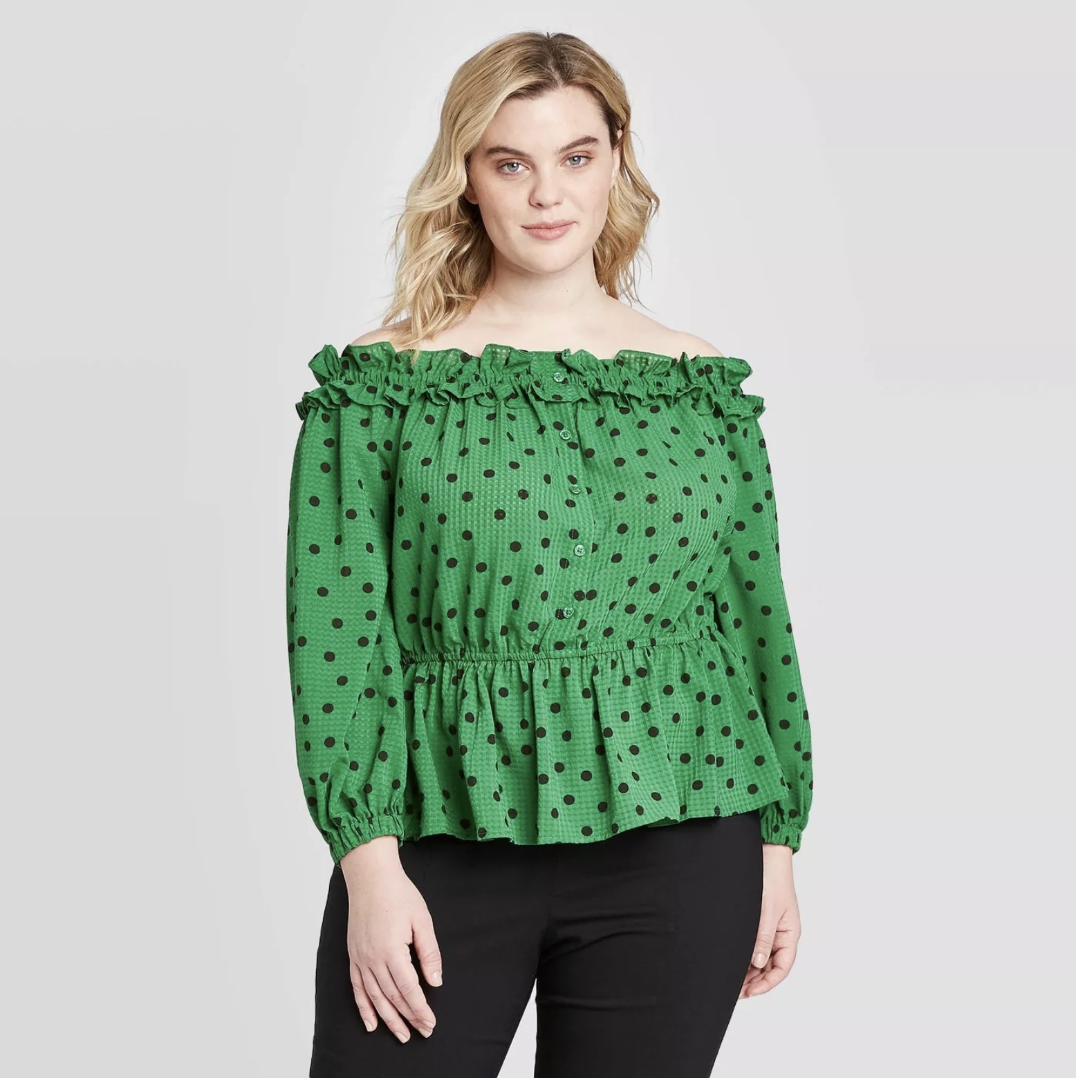 Model is wearing a green smocked off-the-shoulder blouse with small black polka dots