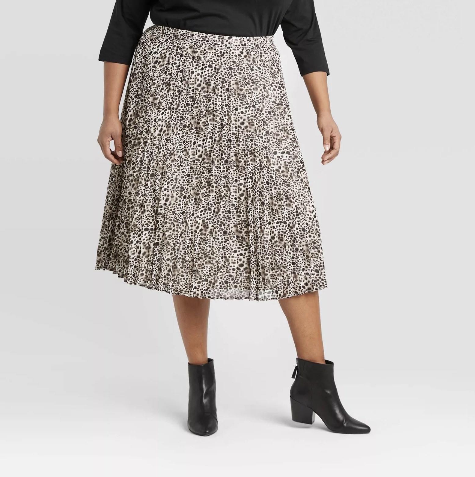 Model is wearing a cream leopard print pleated midi skirt with a pair of black ankle-high chunky booties