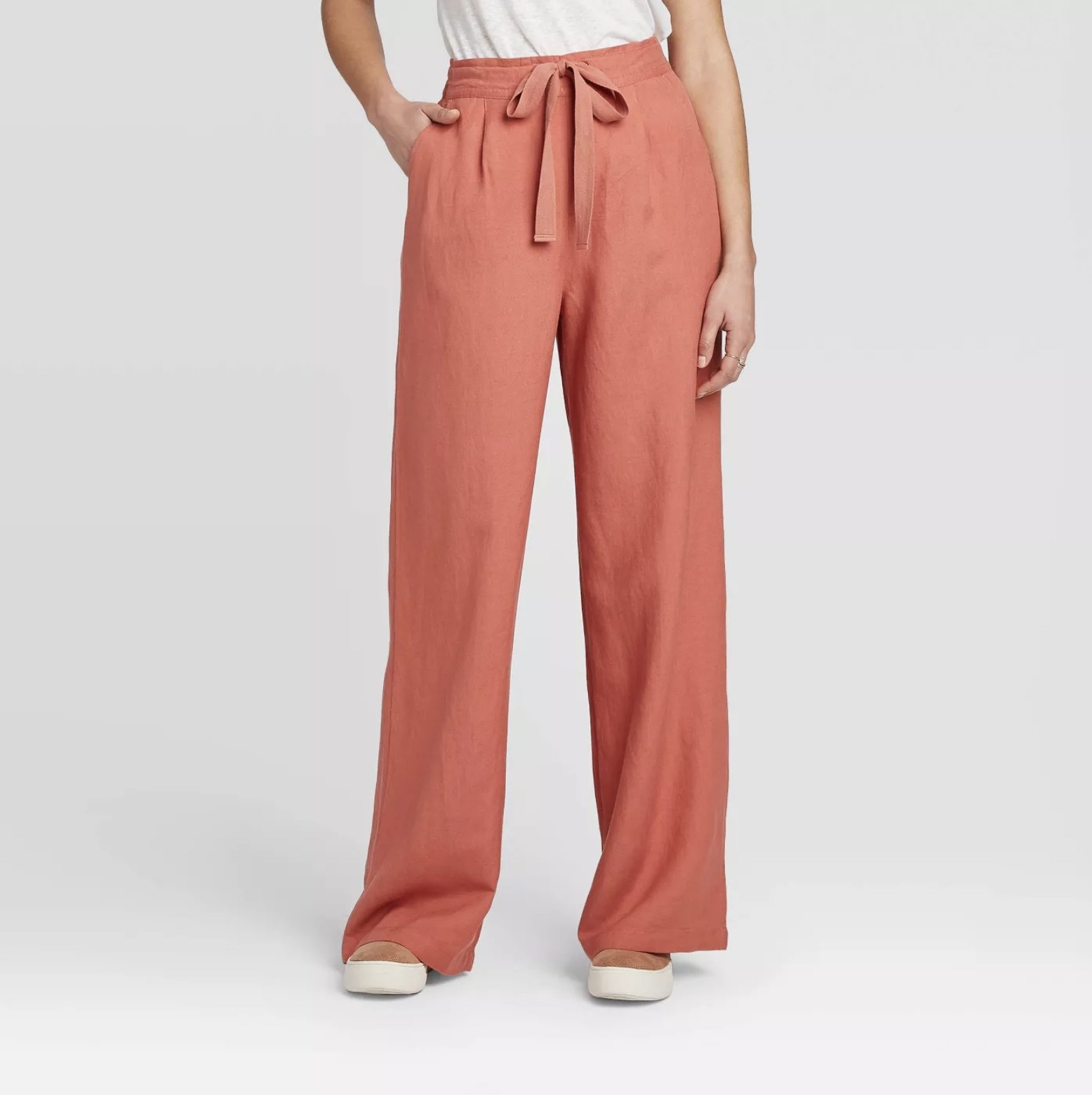 Model is wearing coral wide-leg linen pants with a tie front waist