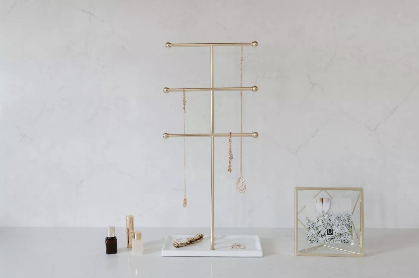 A jewelry stand with a white base and three brass bars