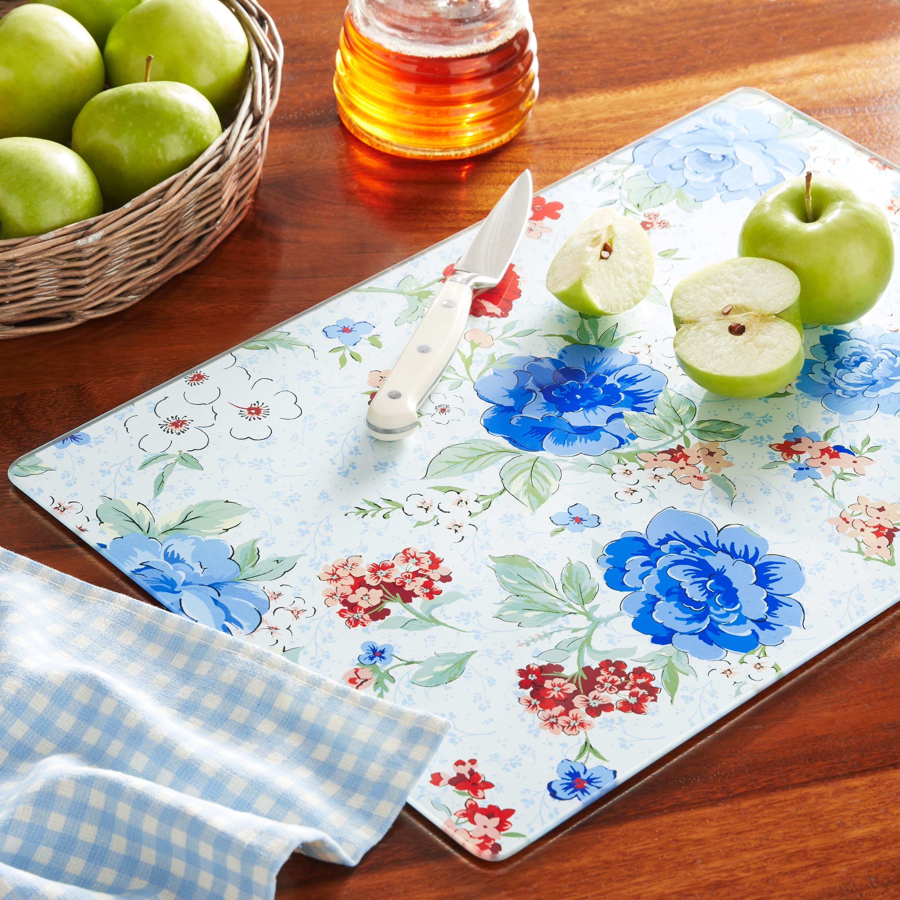 Floral-printed glass cutting board with apples on it