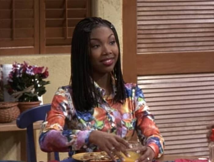 Moesha sits at her dining room table, looking quite fashionable and smart