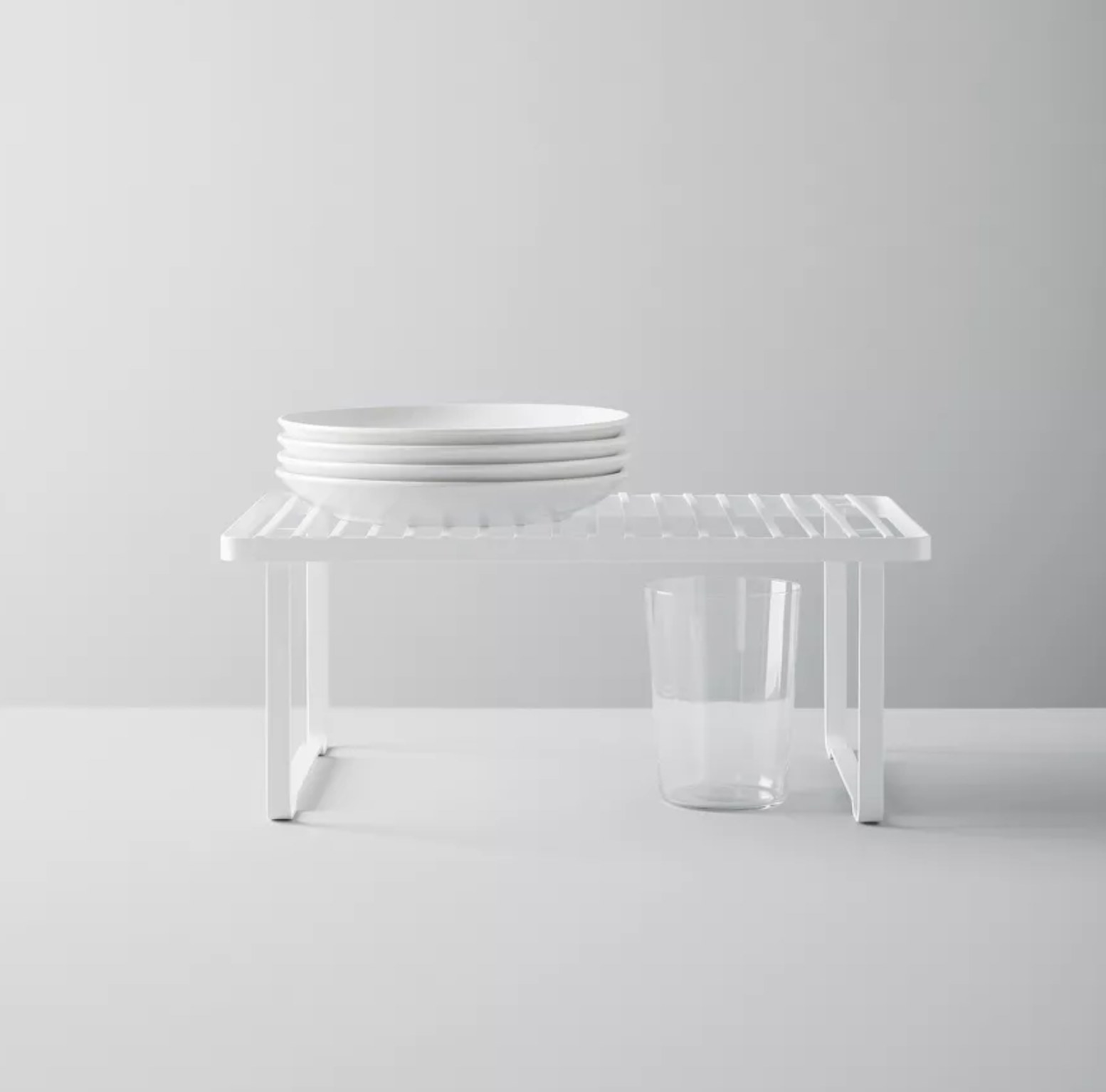 A white shelf holding plates over a glass