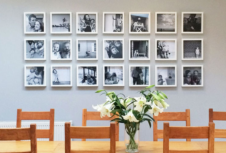 A line of black and white candid family photos framed on the wall