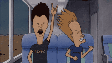 Beavis and Butthead are on a train. Beavis is on the right in a dark blue shirt that says &quot;Metallica&quot;. Butthead is on the left wearing a dark grey shirt that says &quot;AC DC&quot;. They are both head banging 