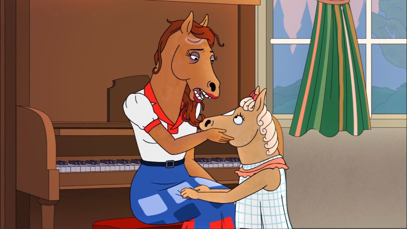Honey Sugarman is a horse wearing a white and red polo shirt with a long blue patched skirt. She has a large scar on her forehead. She is cradling a young horse who is wearing a blue and white checkered dress. 