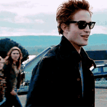 GIF of Edward Cullen walking into school while wearing sunglasses and smiling in Twilight