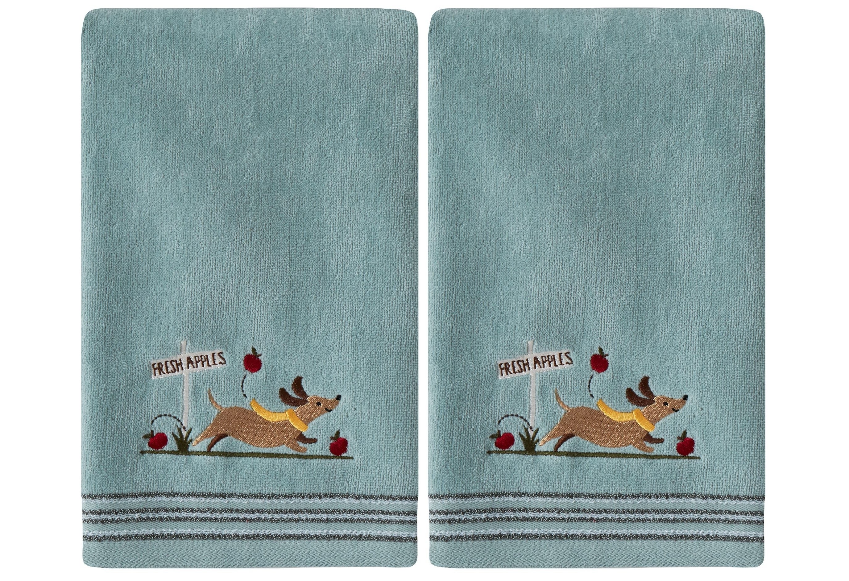 The two blue hand towels with a picture of a dog running with apples and a sign that says &quot;fresh apples&quot; 