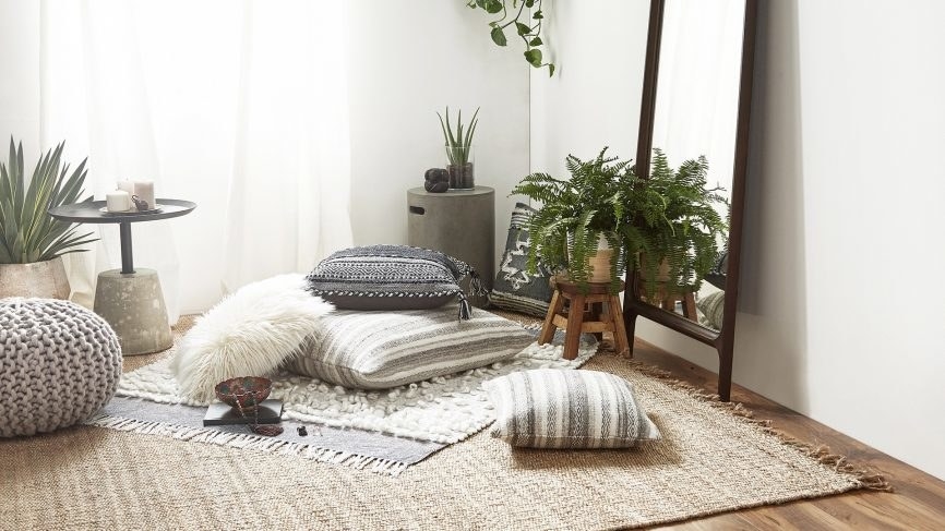 A corner with pillows, a rug, and plants