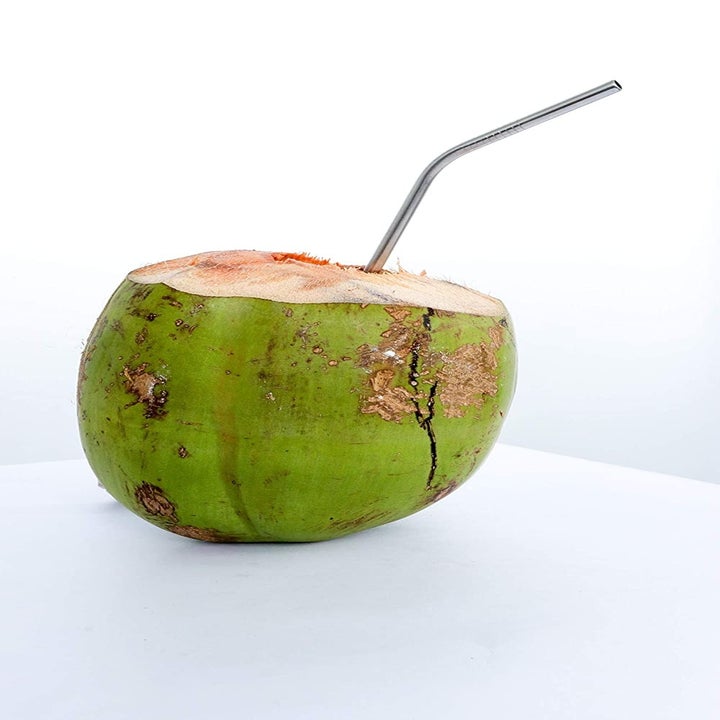 A metal straw in a green coconut.
