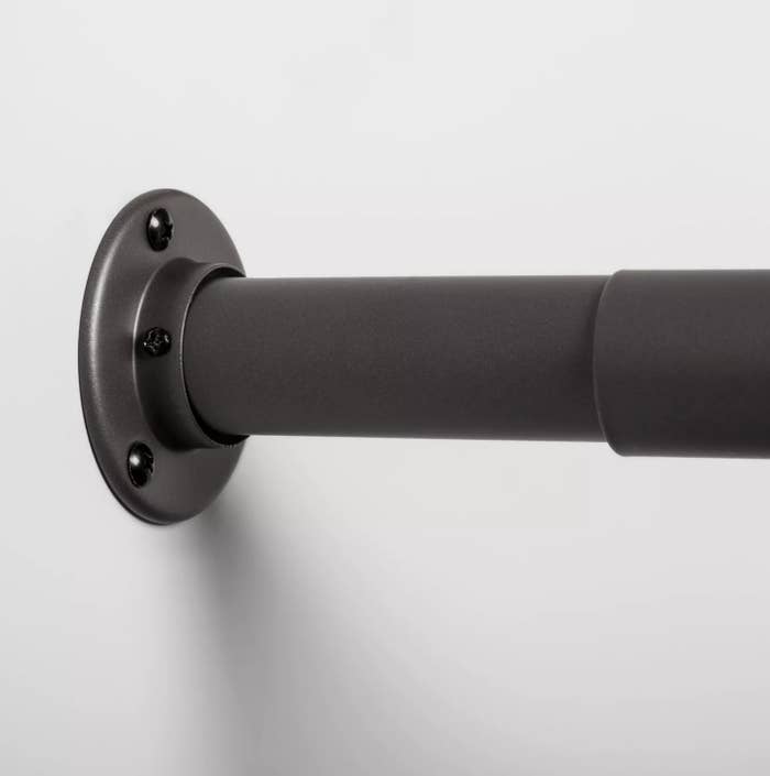 A close-up of the extendable end of a dark gray closet rod.